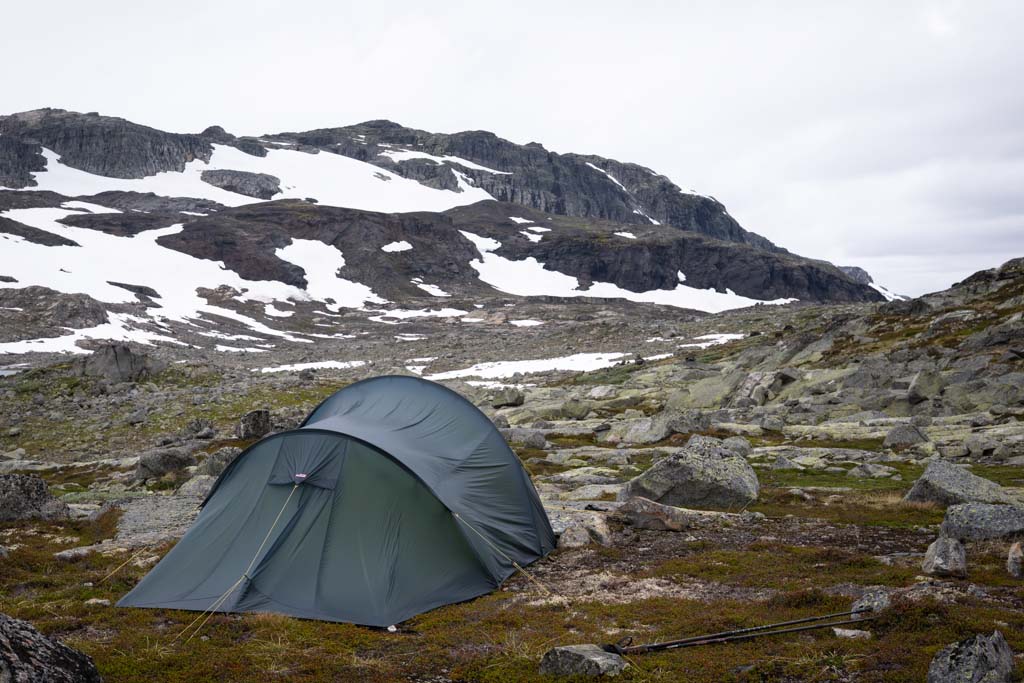 Teltplass ved steinrøys på Hardangervidda nær Finse med fjell i horisonten.
