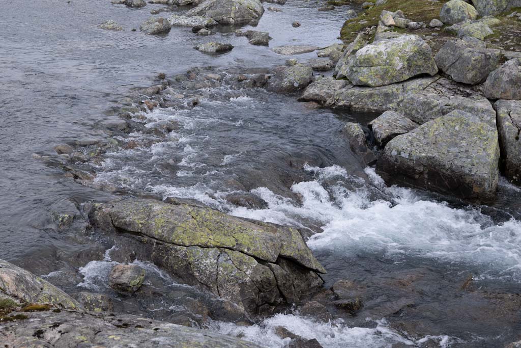 Vandrere som krysser vadeplass ved elv nær Finse på Hardangervidda.