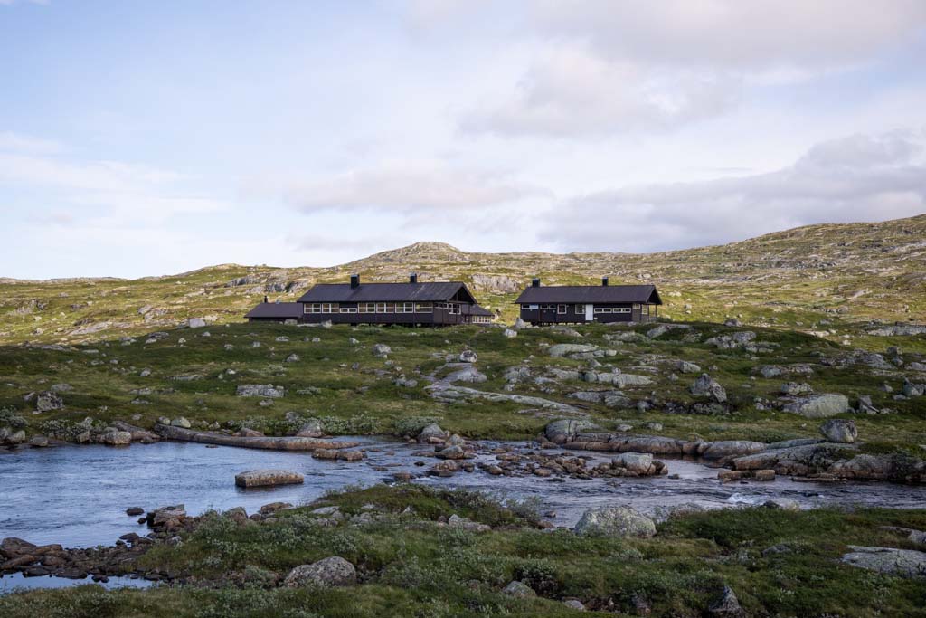 Kjeldebu DNT-hytte omgitt av snøflekker på Hardangervidda.
