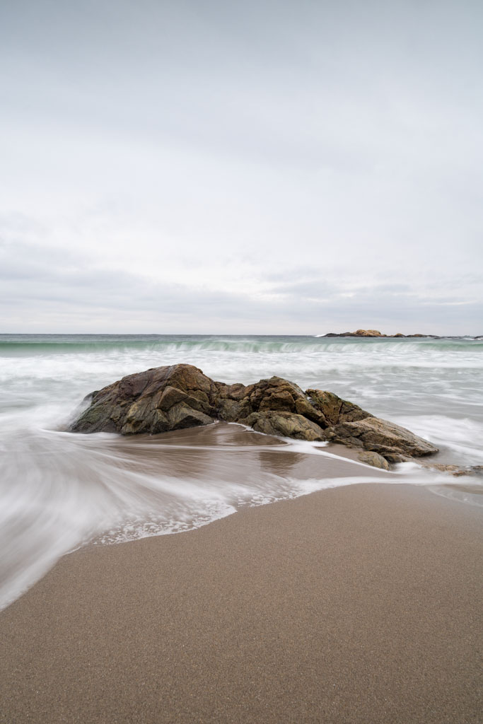 Blankskurte svaberg, sand og rolig hav på Haviksanden.