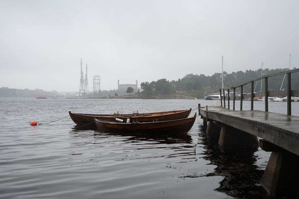 To gamle robåter ved siden av hverandre langs brygga.
