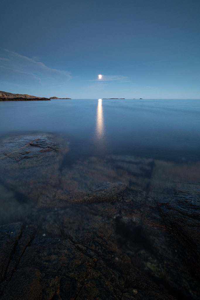 Blåtime over stille vann og mørke skyer like før natt.