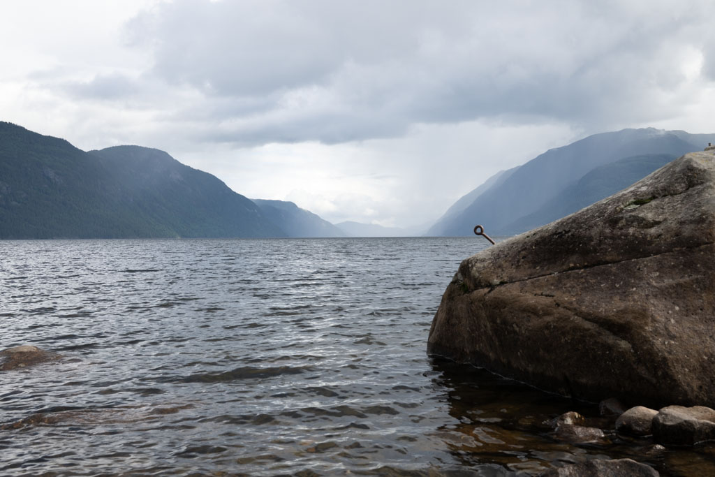 Mørke regnskyer trekker inn over Tinnsjø i Telemark med bølger og fjell i det fjerne.