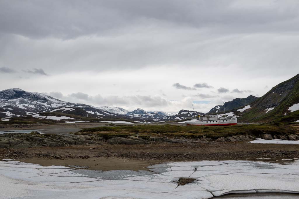 Sykkel og vei langs Bygdin med Bitihorn og fjellrekker i bakgrunnen på Valdresflye.