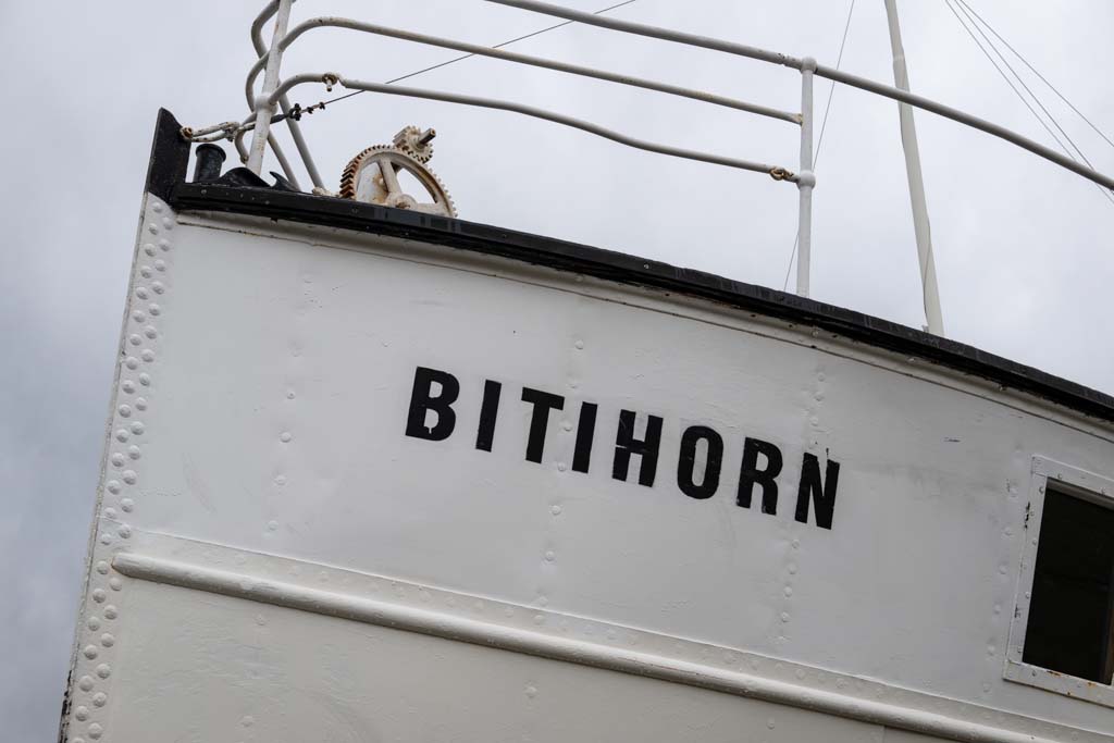 Syklister på vei langs Bygdin med fjellene rundt Bitihorn i bakgrunnen.